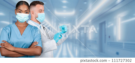 A male and female medical team in a hospital setting, with the man preparing a syringe 111727302