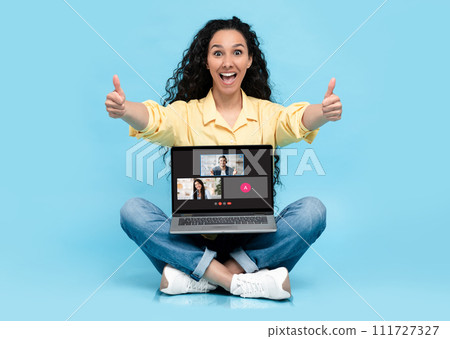 A cheerful young woman in a yellow shirt gives a double thumbs up while sitting A cheerful young woman in a yellow shirt gives a double thumbs up while sitting 111727327