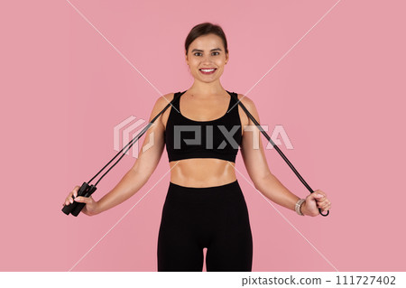 Beautiful sporty woman holding jump rope, ready to start her cardio workout 111727402
