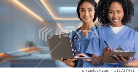 Two female nurses, one holding a laptop and the other writing on a clipboard 111727451