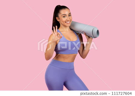 Happy yogi woman with mat makes okay sign, ready for class Happy yogi woman with mat makes okay sign, ready for class 111727604