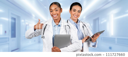 Two smiling female healthcare professionals, one giving a thumbs-up and the other holding a tablet 111727660