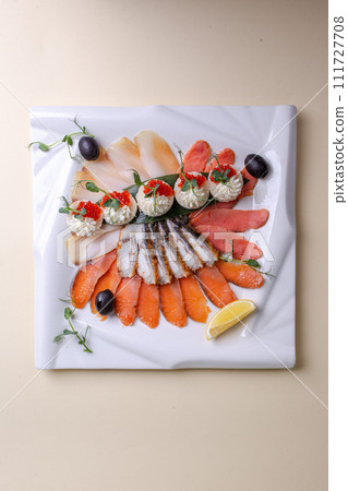 Various seafood on a white plate with lemon and greens. Isolated on a white background Various seafood on a white plate with lemon and greens. Isolated on a white background 111727708