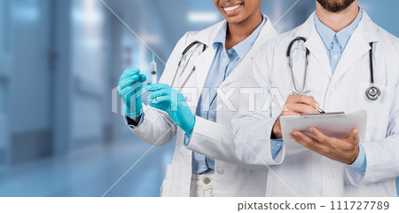 Two medical professionals, a cheerful woman holding a syringe Two medical professionals, a cheerful woman holding a syringe 111727789