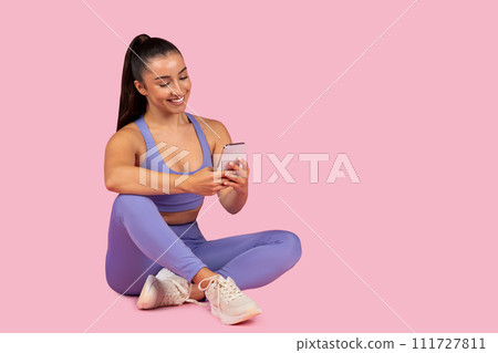 Young woman in activewear using phone post-workout 111727811