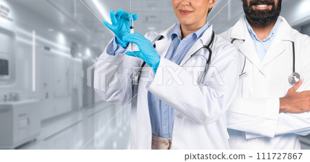 A man and a woman medical professional in white coats stand confidently in a hospital A man and a woman medical professional in white coats stand confidently in a hospital 111727867