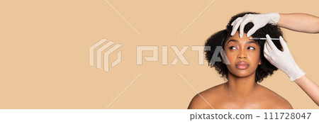 Black woman receiving facial injection treatment, free space 111728047