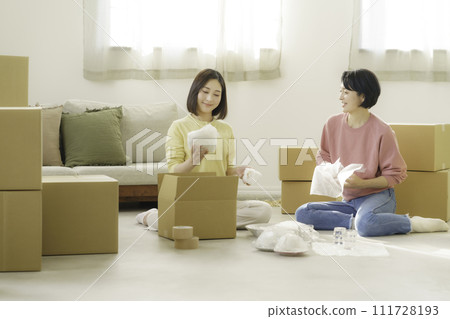 Mother and daughter packing tableware in cardboard boxes for moving Mother and daughter packing tableware in cardboard boxes for moving 111728193