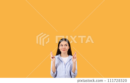 Hopeful lady student crossing fingers on yellow background, free space 111728320