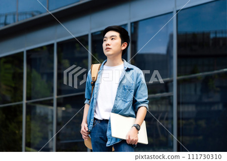 Portrait of handsome Asian student holding computer laptop and backpack 111730310