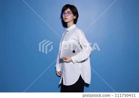 A young woman wearing glasses photographed against a blue background 111730431