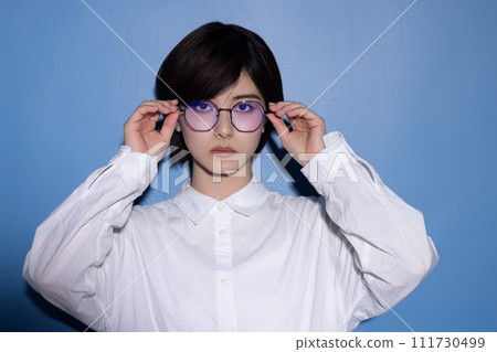 藍色背景下拍攝的一位戴眼鏡的年輕女子 111730499