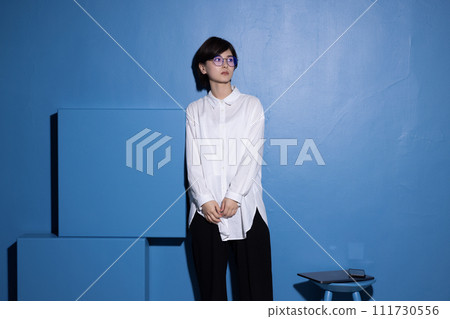 藍色背景下拍攝的一位戴眼鏡的年輕女子 111730556