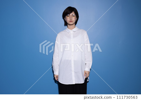 A young woman wearing glasses photographed against a blue background 111730563