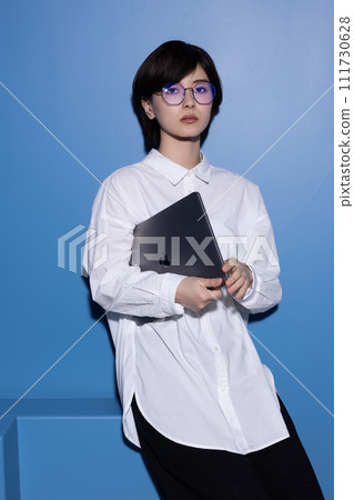 藍色背景下拍攝的一位戴眼鏡的年輕女子 藍色背景下拍攝的一位戴眼鏡的年輕女子 111730628
