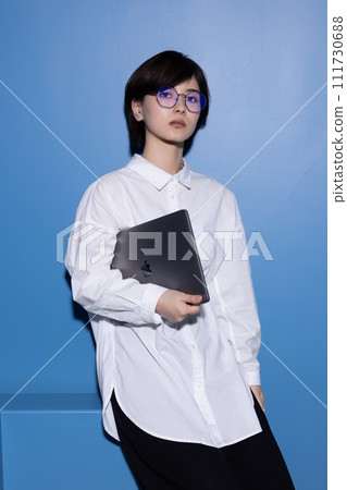 A young woman wearing glasses photographed against a blue background 111730688