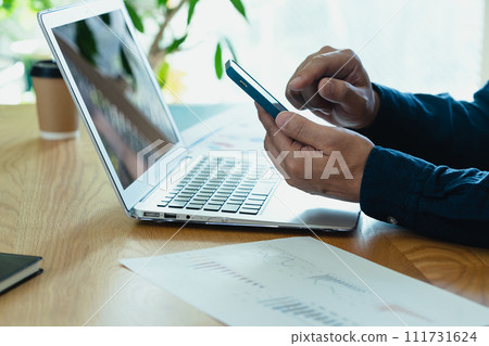 Hands of a man operating a computer and smartphone 111731624