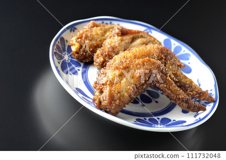 Deep-fried chicken wings photographed against a black background 111732048