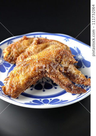Deep-fried chicken wings photographed against a black background 111732064