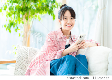 Young woman looking at her smartphone in the living room 111734546