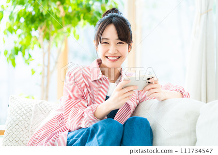 Young woman looking at her smartphone in the living room 111734547