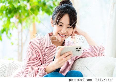 Young woman looking at her smartphone in the living room 111734548