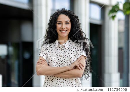 Smiling professional woman with curly hair on a break outdoors near corporate office, exemplifying business confidence. Smiling professional woman with curly hair on a break outdoors near corporate office, exemplifying business confidence. 111734996