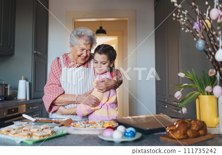 Grandmother with grandaughter preparing traditional easter meals, baking cakes and sweets. Passing down family recipes, custom and stories. 111735242