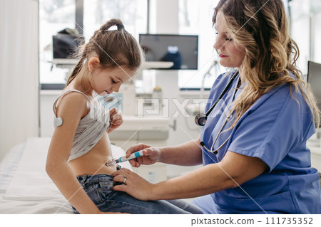 Nurse injecting insulin in diabetic girl belly. Close up of young girl with type 1 diabetes taking insuling with syringe needle. 111735352