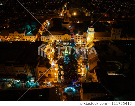 Aerial night shot of city during Christmas, winter and christmas decorations on square. Chistmas market during holiday season in small city. Aerial night shot of city during Christmas, winter and christmas decorations on square. Chistmas market during holiday season in small city. 111735413