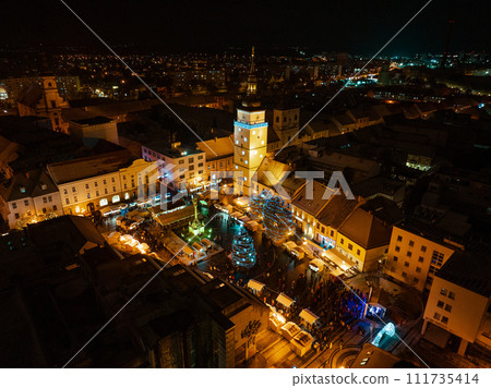 Aerial night shot of city during Christmas, winter and christmas decorations on square. Chistmas market during holiday season in small city. Aerial night shot of city during Christmas, winter and christmas decorations on square. Chistmas market during holiday season in small city. 111735414