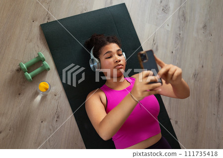 Woman resting after home workout, New Year's resolutions, healthy lifestyle, losing weight and selfcare. Concept of morning or evening exercise. 111735418
