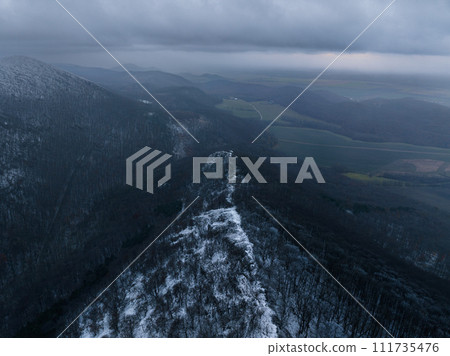 Aerial view of old ruins of fortress in the middle of winter forest. Drone view of snowy landscape with broken stone walls. Aerial view of old ruins of fortress in the middle of winter forest. Drone view of snowy landscape with broken stone walls. 111735476