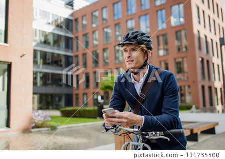 Handsome middle-aged man commuting through the city by bike in suit. Male city commuter traveling from work by bike after a long workday. 111735500