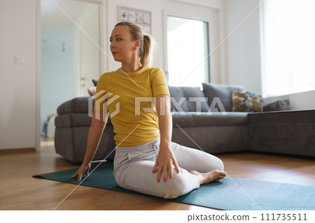 Woman exercising at home, stretching her body. Solo home workout and meditation, morning or evening workout routine. 111735511