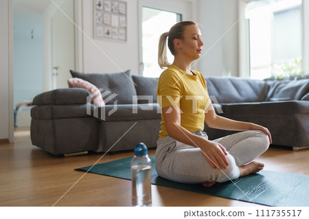 Woman exercising at home, stretching her body. Solo home workout and meditation, morning or evening workout routine. Woman exercising at home, stretching her body. Solo home workout and meditation, morning or evening workout routine. 111735517