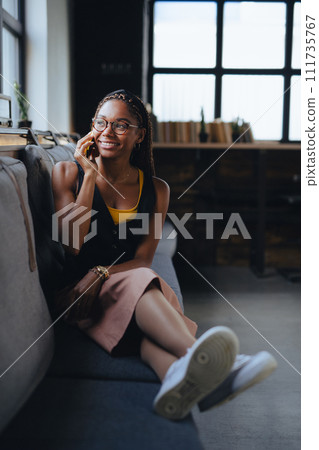 Portrait of beautiful woman sitting in modern office and making phone call, smiling. Working remotely from coffee shop. Portrait of beautiful woman sitting in modern office and making phone call, smiling. Working remotely from coffee shop. 111735767