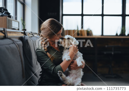 Portrait of beautiful young woman holding her dog in hands. Cute white dog in arms of loving owner. With dog in coffe shop. 111735773