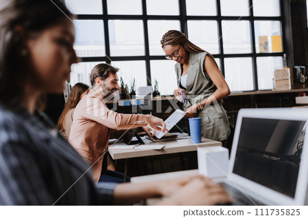 People in coworking space sharing ideas, collaboring, talking about business project. Group of freelancers and remote businesspeople working in shared work area. Concept of coworking as modern working 111735825