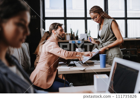 People in coworking space sharing ideas, collaboring, talking about business project. Group of freelancers and remote businesspeople working in shared work area. Concept of coworking as modern working 111735826