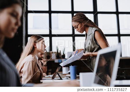 People in coworking space sharing ideas, collaboring, talking about business project. Group of freelancers and remote businesspeople working in shared work area. Concept of coworking as modern working 111735827