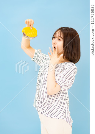 Young woman in her 20s worried about money and wallet, vertical position Young woman in her 20s worried about money and wallet, vertical position 111736083