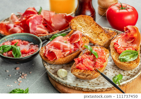 Spanish breakfast. Jamon Iberico ham and tomate bread with coffee and juice on a light background Spanish breakfast. Jamon Iberico ham and tomate bread with coffee and juice on a light background 111737450