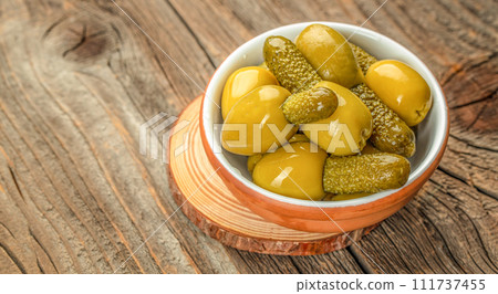 Olives with cornichons on a wooden board. Concept healthy and balanced eating. place for text, top view Olives with cornichons on a wooden board. Concept healthy and balanced eating. place for text, top view 111737455