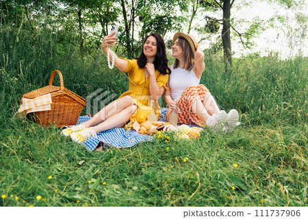 Two girls take selfie on blue blanket for an outdoor picnic 111737906