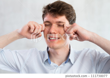 Portrait of young guy with itchy eyes in studio Portrait of young guy with itchy eyes in studio 111738077