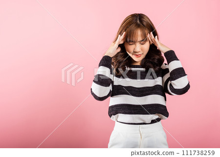 Portrait of beautiful Asian young woman sad tired strain face holding hold head by hands, stress female person unhappy closed eyes problem she headache, studio shot isolated on pink background 111738259
