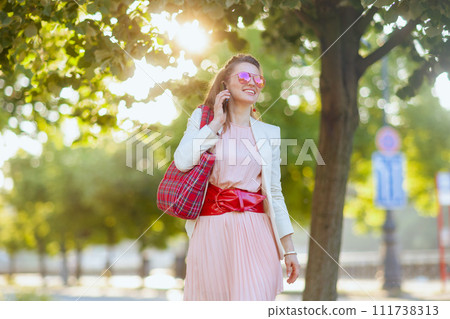 smiling stylish female in city speaking on smartphone smiling stylish female in city speaking on smartphone 111738313