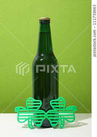 Green bottle and glasses on white table on green background 111738663