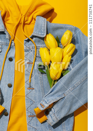 Hoodie, jeans jacket and flowers on yellow background, close up 111738741